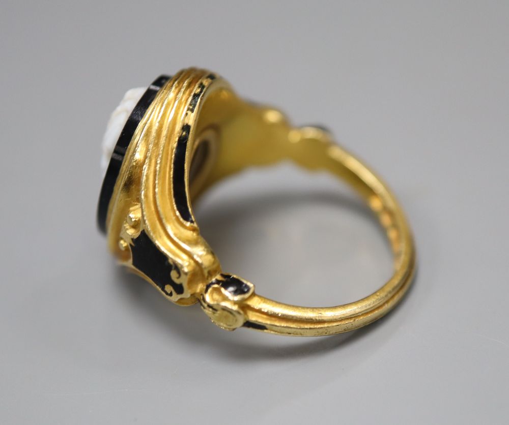 A Victorian 18ct gold cameo ring, of carved scrolled design with black enamelled decoration and hairwork panel, size M/N,